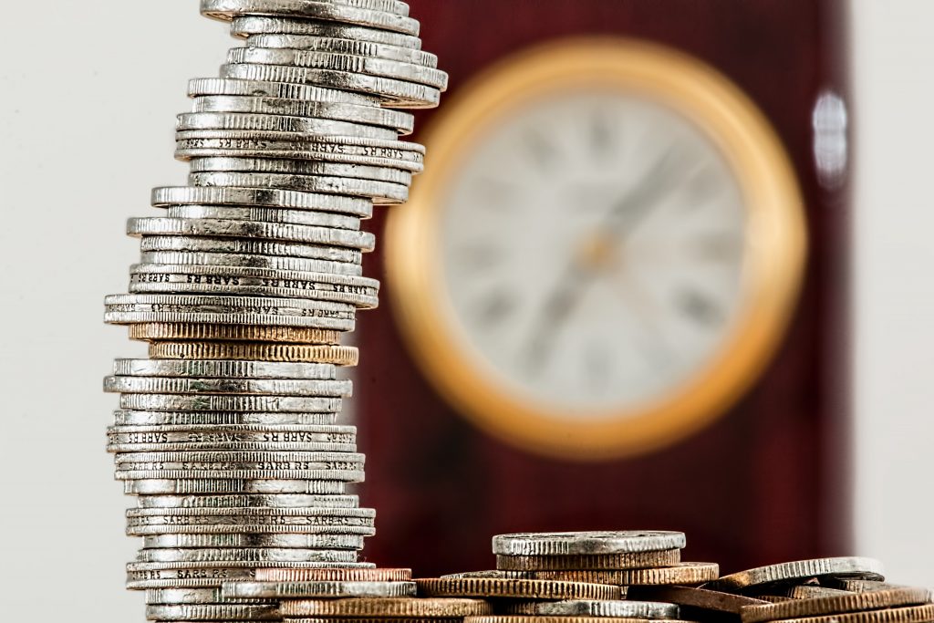 stack of silver and copper coins in front of clock